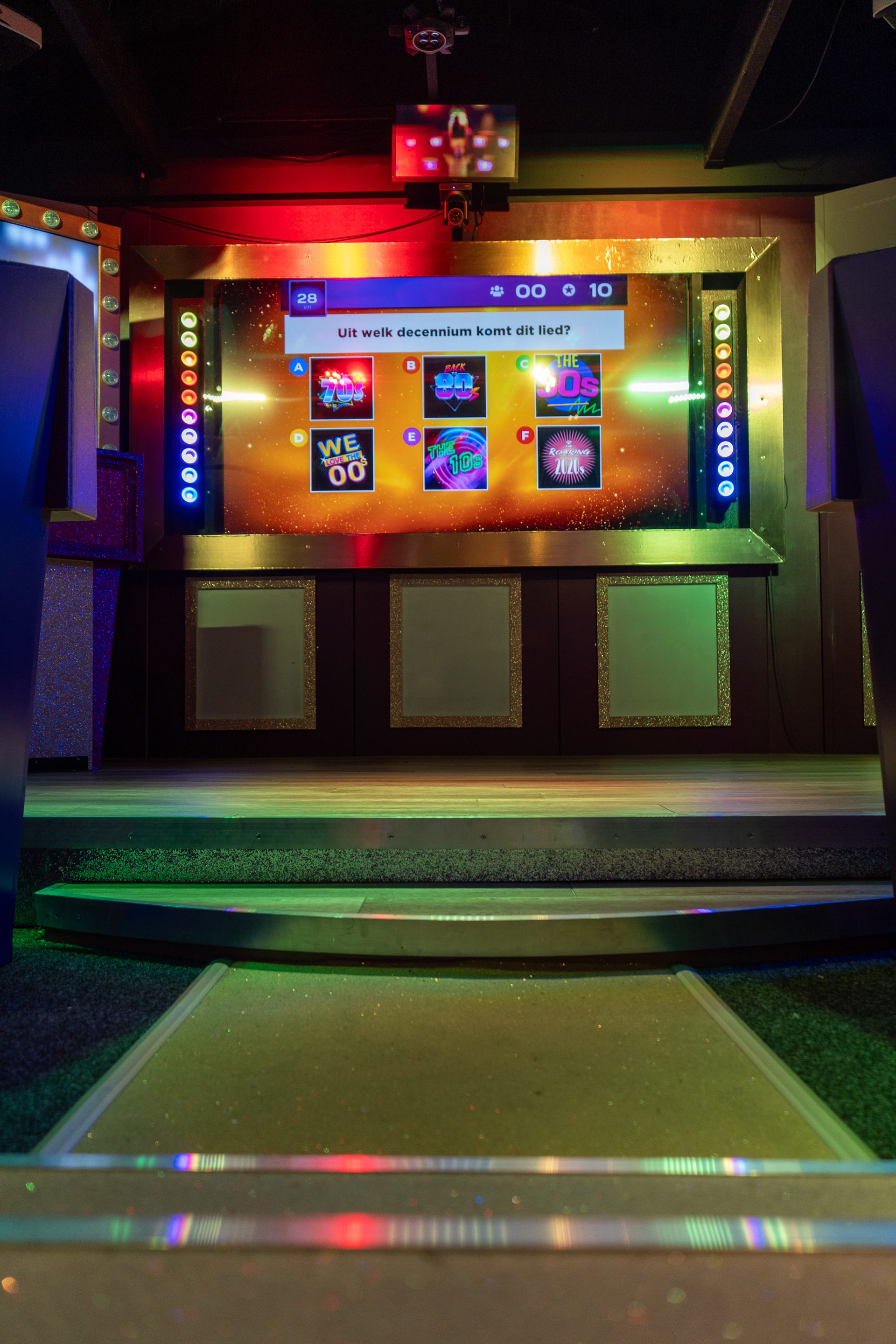 Arena-opstelling met quizscherm en roze showlicht