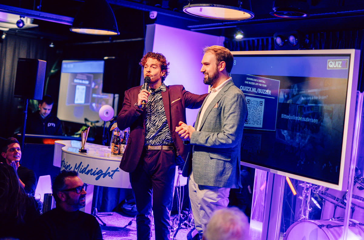 QuizX hosts on stage next to the quiz screen
