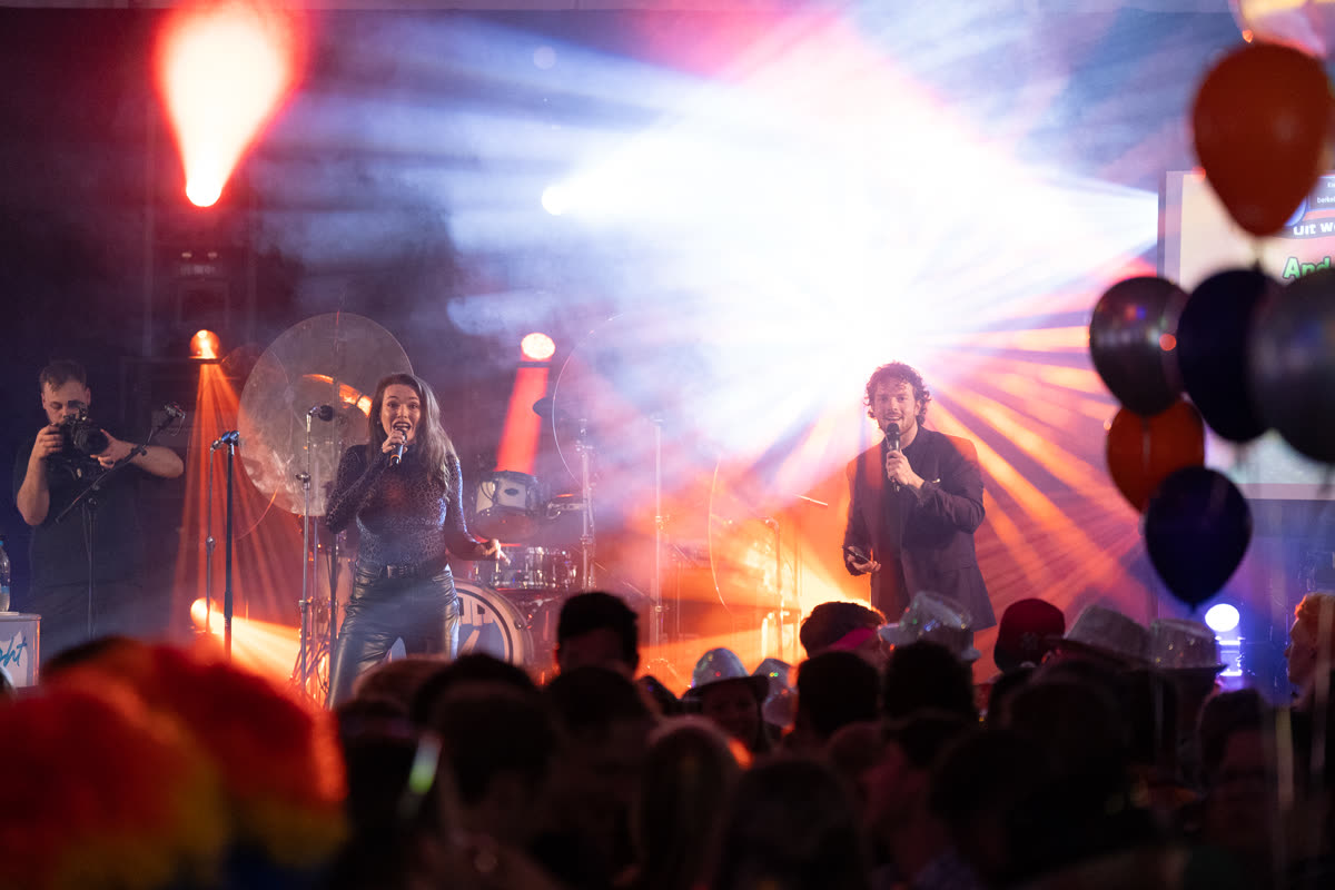 Two QuizX hosts presenting a live show with band