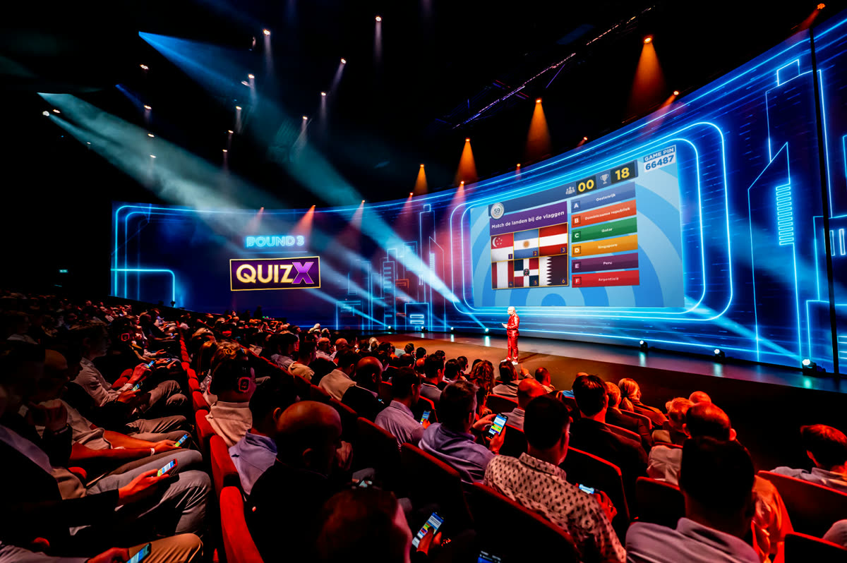 QuizX quiz show in a packed theater with giant LED wall