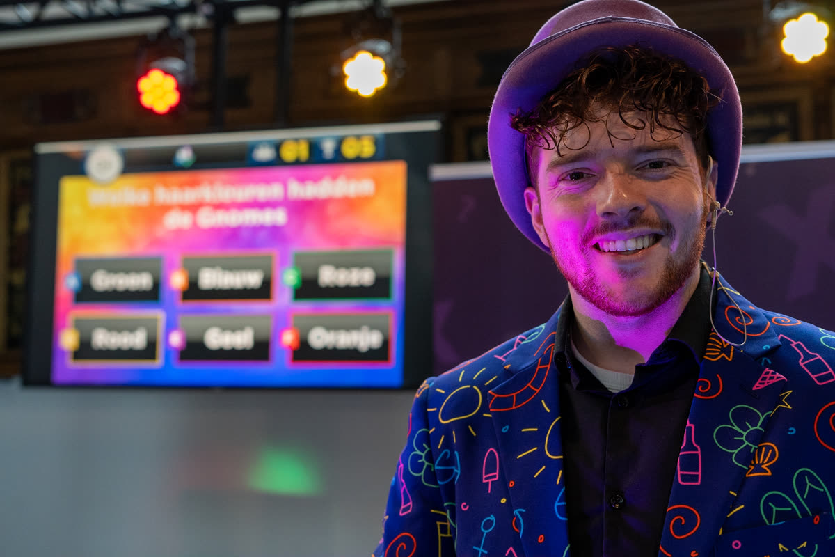 Animateur en costume coloré devant l'écran de quiz